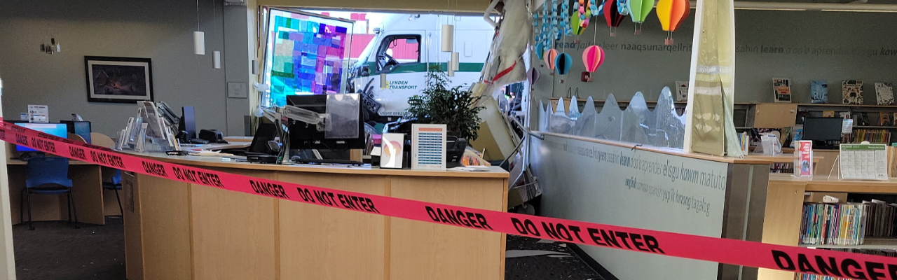 Photo showing the damage done to the Mountain View Library when hit by a Semi truck. There is broken glass and water damage.