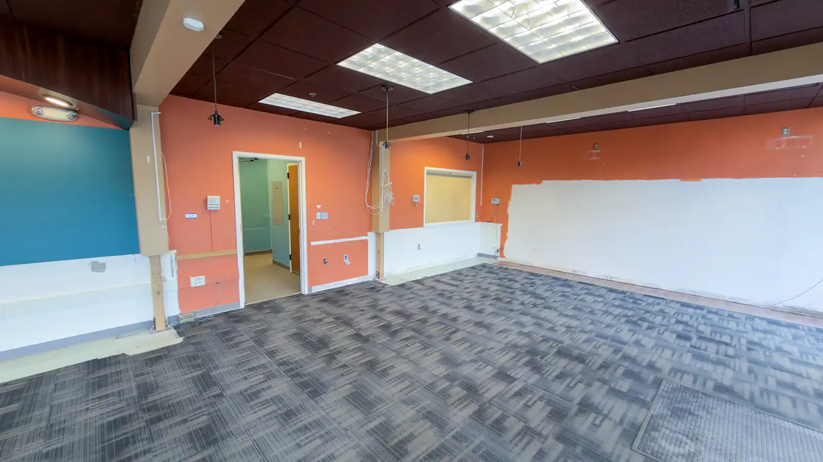 Historic City Hall interior during renovation, with exposed hanging wiring, partially stripped and patched walls, and carpet tiles